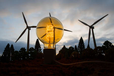 Electricity power in nature or clean energy concept. Wind Turbine producing alternative energy at sunset. Creative decoration with small miniature. Selective focusの写真素材