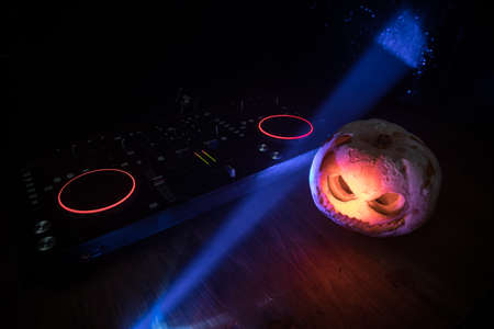 Halloween pumpkin on a dj table with headphones on dark background with copy space. Happy Halloween...