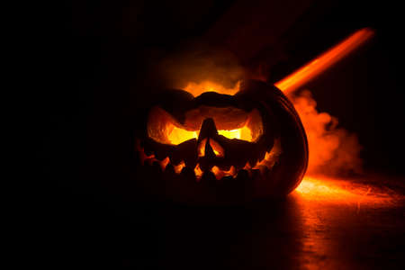 Halloween pumpkin smile and scary eyes for party night. Close up view of scary Halloween pumpkin with eyes glowing inside at black background. Selective focusの写真素材