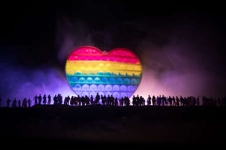 lgbt rights concept, Silhouette of crowd standing against a heart painted like a LGBT flag in dark background. Selective focusの写真素材