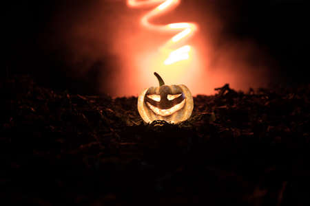 halloween jack-o-lantern on autumn leaves. Scary Halloween Pumpkin looking through the smoke....