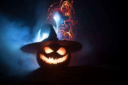 Halloween pumpkin smile and scary eyes for party night. Close up view of scary Halloween pumpkin with eyes glowing inside at black background. Selective focusの写真素材