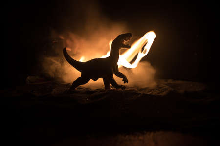 Silhouette of giant Dinosaur in foggy night. Creative decoration with little miniature. Burning misty background. Selective focusの写真素材