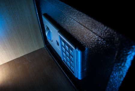 Small modern safe on shelf in dark. Small safe box close up in low key light. Selective focus