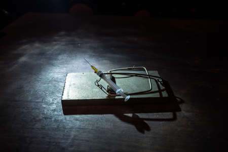 Syringe on mousetrap. Abstract green Corona virus novel miniature. Creative decoration with fog and backlight. Selective focusの写真素材