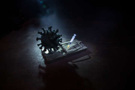 Corona virus Vaccine concept with syringe on mousetrap. Abstract green Corona virus novel miniature. Creative decoration with fog and backlight. Selective focusの写真素材