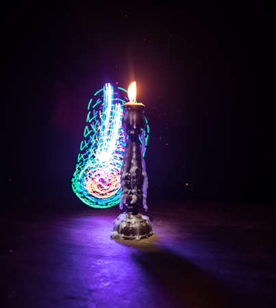 Single burning candle. Light of flame and flowing candle wax, dark background. Selective focus
