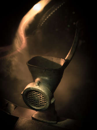 Close-up view of the old manual meat grinder. Horror concept with burning foggy background....