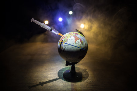 virus Vaccine concept with syringe and green virus novel miniature. Vaccine Concept of fight against virus. Creative decoration with fog and backlight. Selective focusの写真素材