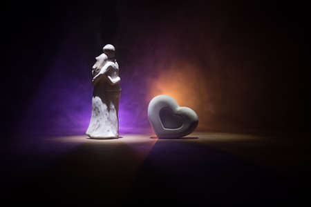 Valentines background. Valentine's Day heart on a dark wooden table. Little love couple figure close...