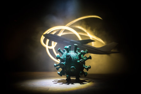 and travel concept. Business and tourism hit by virus during pandemic. Artwork decoration. White passenger plane and virus miniature in dark. Selective focusの写真素材