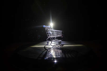 Empty shopping trolley on dark toned foggy background with some copy space. Financial crisis concept. Selective focusの写真素材