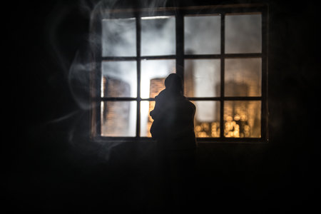 Beautiful view of a miniature city at night from window of dollhouse. Romantic couple at window. Artwork table decoration with handmade realistic dollhouse. Selective focus.の写真素材
