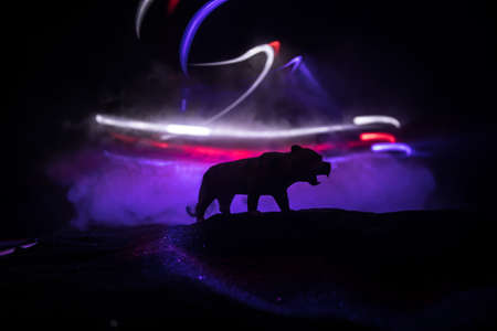 Silhouette of a tiger miniature standing at foggy night. Creative decoration with colorful backlight with fog. Selective focusの写真素材