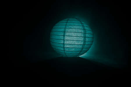 Beautiful paper lantern glowing on wooden table in dark. Selective focusの写真素材
