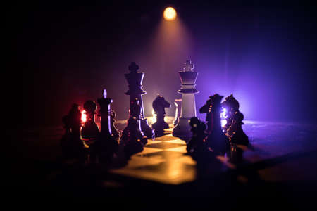 Beautiful crown miniature on chessboard. chess board game concept of business ideas and competition and strategy ideas concept. Chess figures on a dark background with smoke and fog. Selective focusの写真素材