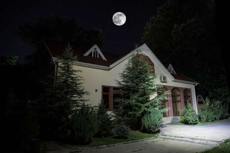 Old house with a Ghost in the forest at night or Abandoned Haunted Horror House in fog. Old mystic building in dead tree forest. Trees at night with moon. Surreal lights. Horror halloween conceptの写真素材