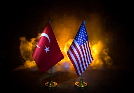 Turkey and USA small flags on burning dark background. Concept of crisis of war and political conflicts between nations. Selective focusの写真素材