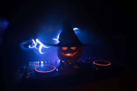 Halloween pumpkin on a dj table with headphones on dark background with copy space. Happy Halloween festival decorations and music conceptの写真素材