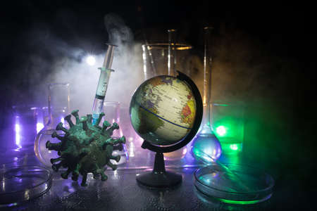 Corona virus Vaccine concept with syringe and green Corona virus novel miniature. Vaccine Concept of fight against coronavirus. Creative decoration with fog and backlight. Selective focusの写真素材