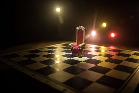 Red royal chair miniature on wooden table. Medieval Throne on chessboard. Chess board game concept of business ideas and competition and strategy ideas concept. Selective focusの写真素材