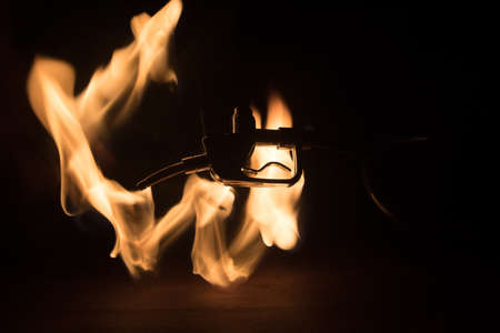 Creative concept. Silhouette of gasoline pistol miniature on dark toned foggy background. Fuel gun close up burning. Selective focusの写真素材