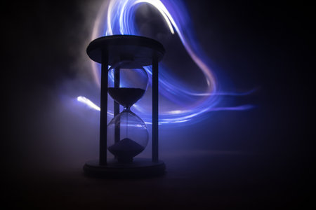 Time concept. Silhouette of Hourglass clock on dark toned background. Abstract concept with copy...