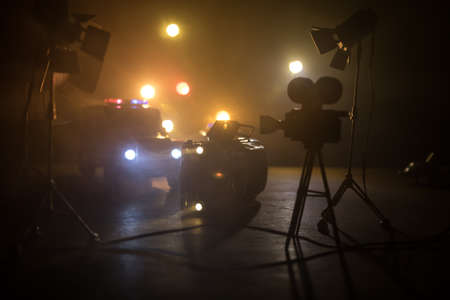 Action movie concept. Police cars and miniature movie set on dark toned background with fog. Police car chasing a car at night. Scene of crime accident. Selective focusの写真素材