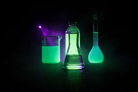 Pharmacy and chemistry theme. Test glass flask with solution in research laboratory. Science and medical background. Laboratory test tubes on dark toned background, science research equipment conceptの写真素材