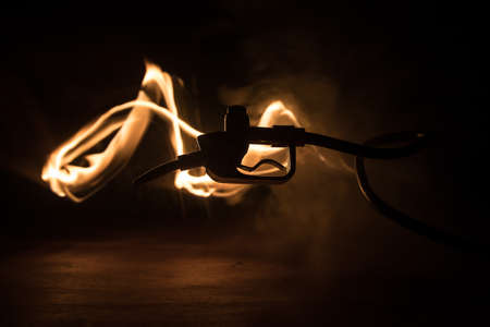 Creative concept. Silhouette of gasoline pistol miniature on dark toned foggy background. Fuel gun...