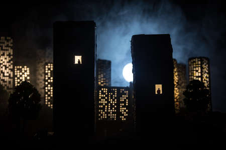 concept of loneliness, in the form of a silhouette of woman and man in a city window at night. Symbol of expectation, dreams and destinies. Creative decoration with City miniature. Selective focusの写真素材