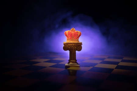 Beautiful Crown on chessboard. chess board game concept of business ideas and competition and strategy ideas concept. Chess figures on a dark background with smoke and fog. Selective focusの写真素材