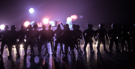 Anti-riot police give signal to be ready. Government power concept. Spec ops police in action. Smoke on a dark background with lights. Blue red flashing sirens. Selective focusの写真素材