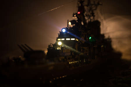 War concept. Night battle scene at sea. Dramatic toned clouds effect. Silhouette of the battle ship in night. Miniature creative table decoration. Selective focusの写真素材