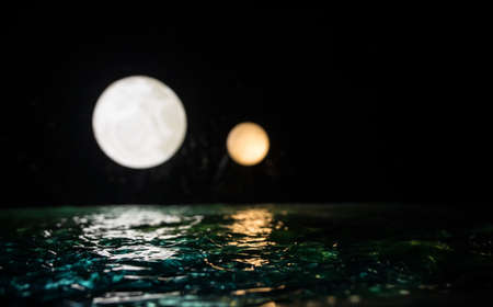 Fantasy concept. Full moon on sea to night. Table decoration with two moon miniatures over water. Selective focusの写真素材
