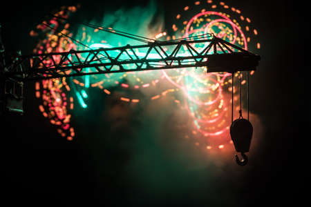 Abstract Industrial background with construction crane silhouette over amazing night sky with fog and backlight. Tower crane against the foggy sky at night. Industrial skyline. Selective focusの写真素材