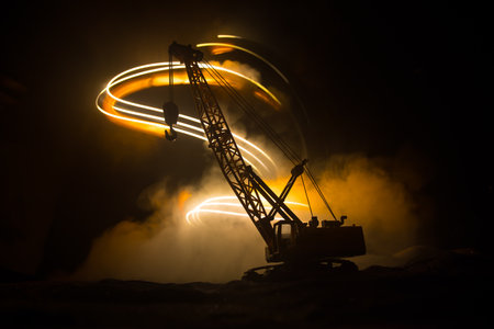 Abstract Industrial background with construction crane silhouette over amazing night sky with fog and backlight. Tower crane against the foggy sky at night. Industrial skyline. Selective focusの写真素材