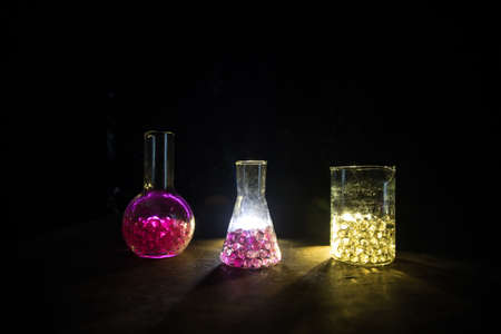 Pharmacy and chemistry theme. Test glass flask with solution in research laboratory. Science and medical background. Laboratory test tubes on dark toned background, science research equipment conceptの写真素材
