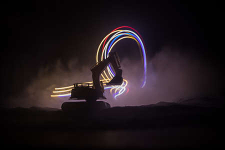 Construction site on a city street. A yellow digger excavator parked during the night on a...