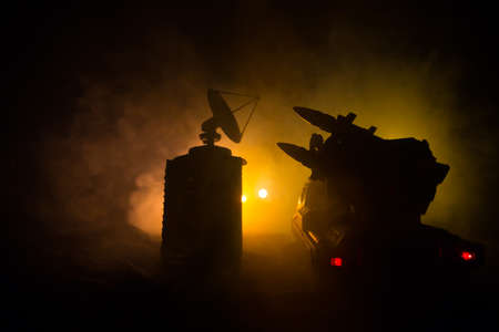 Creative artwork decoration. Silhouette of mobile air defense truck with radar antenna at night. Rocket launcher aimed at sky ready to attack. Selective focusの写真素材