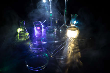 Pharmacy and chemistry theme. Test glass flask with solution in research laboratory. Science and medical background. Laboratory test tubes on dark toned background, science research equipment conceptの写真素材