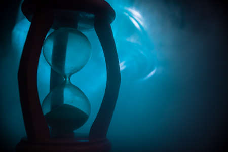Time concept. Silhouette of Hourglass clock on dark toned background. Abstract concept with copy space. Selective focusの写真素材