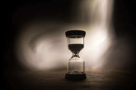 Time concept. Silhouette of Hourglass clock on dark toned background. Abstract concept with copy space. Selective focusの写真素材