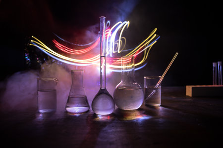 Pharmacy and chemistry theme. Test glass flask with solution in research laboratory. Science and medical background. Laboratory test tubes on dark toned background, science research equipment conceptの写真素材