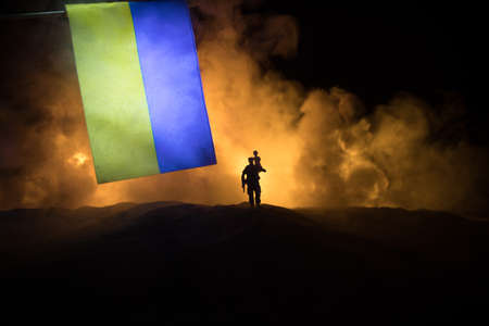 Silhouette soldier carrying little boy on his shoulder from fire. Russian war in Ukraine concept. Man moving out with little boy from burned out city destroyed in war. selective focusの写真素材