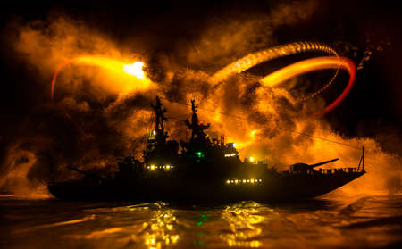 War concept. Night battle scene at sea. Dramatic toned clouds effect. Silhouette of the battle ship in night. Miniature creative table decoration. Selective focusの写真素材