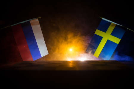 Flags of Sweden and Russia on dark background. Conceptual image of war between Russia and Sweden using national flags . selective focusの写真素材