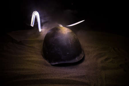 Soviet army Helmet Second World War on sand with backlight and smoke. war concept. selective focus