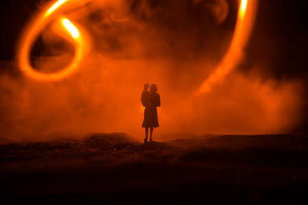 Silhouette of woman with child walking at cemetery at night. Horror Halloween concept. Artwork table...