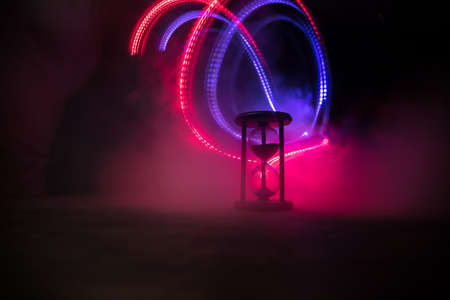 Time concept. Silhouette of Hourglass clock on dark toned background. Abstract concept with copy...